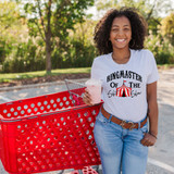 Ringmaster Of The Shit Show DTF Transfer, a woman wearing a white T-shirt with the product design, holding a pink beverage, standing beside a red shopping cart outdoors.