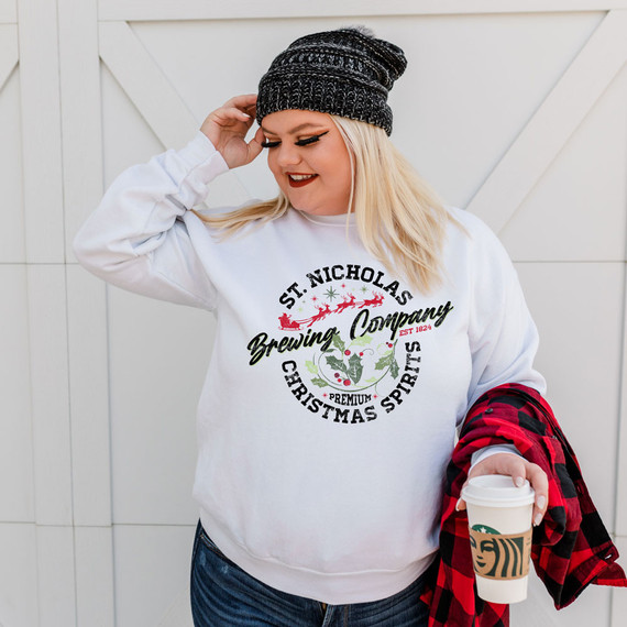 St. Nicholas Brewing Company DTF Heat Transfer, woman wearing holiday-themed sweatshirt with Christmas design, holding a Starbucks coffee cup.