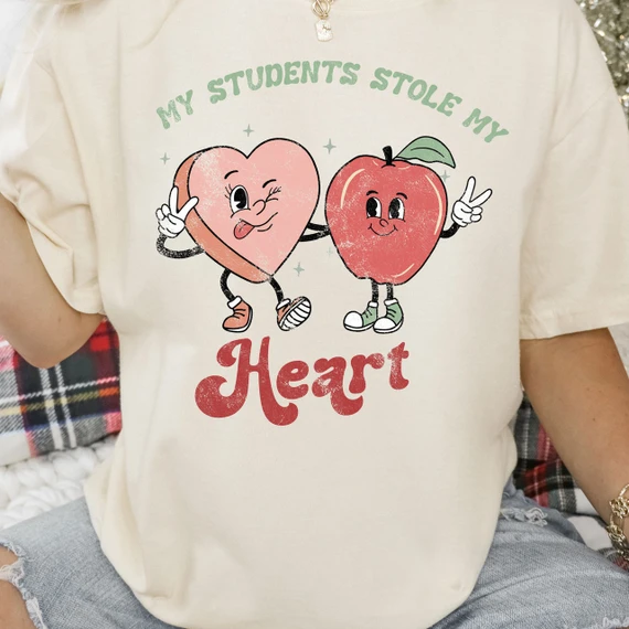 My Students Stole My Heart Screen Print Heat Transfer, cute cartoon heart and apple characters holding hands and making peace signs with a distressed texture design.
