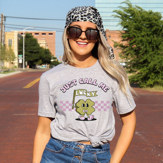 Just Call Me Lucky DTF Heat Transfer, image of a woman wearing a t-shirt with a Lucky character holding a flag and the text "Just Call Me Lucky" on it.