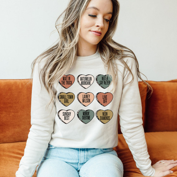 Lainey Candy Hearts DTF Heat Transfer, colorful heart-shaped designs with various phrases on a woman's white sweatshirt.