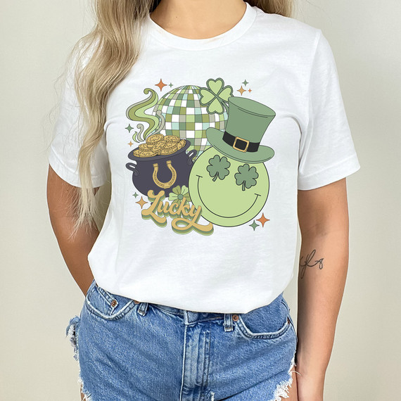 Lucky Collage DTF Heat Transfer, St. Patrick's Day-themed graphic on a white T-shirt featuring a pot of gold, a smiling shamrock face wearing a leprechaun hat, a glittering disco ball, and the word "Lucky" in stylized lettering.