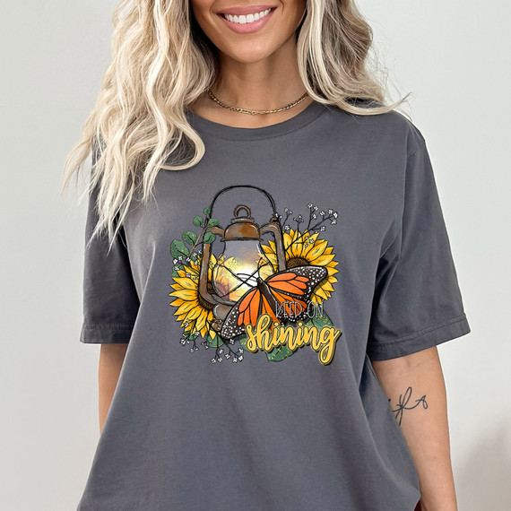 Keep On Shining DTF Heat Transfer, a vibrant design with a lantern, sunflower, and butterfly on a gray t-shirt.