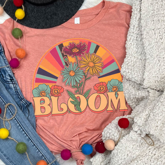 Bloom Retro Screen Print Heat Transfer, colorful floral illustration with the word 'BLOOM' on a pink T-shirt surrounded by clothing and decorative items.