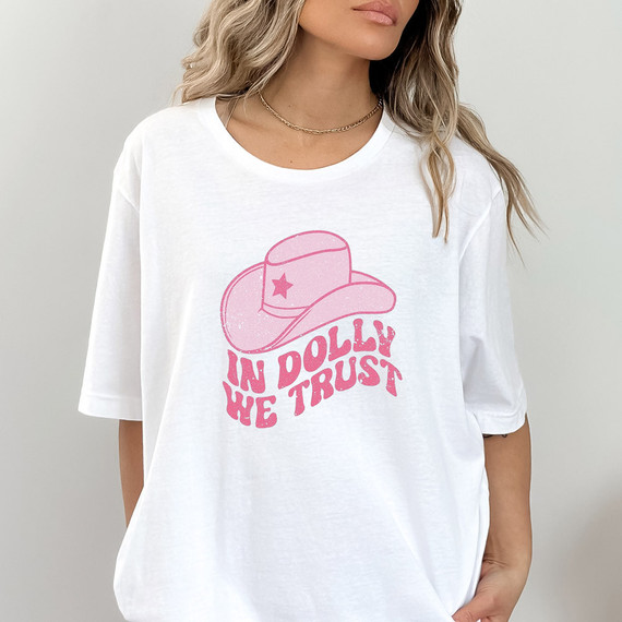 In Dolly We Trust DTF Heat Transfer, pink graphic of a cowboy hat with a star and the phrase 'In Dolly We Trust' on a white T-shirt.