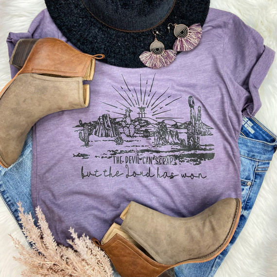 The Devil Can Scrap Screen Print Heat Transfer, a graphic design featuring desert scenes with cacti, mountains, and the sun, printed on a purple T-shirt.