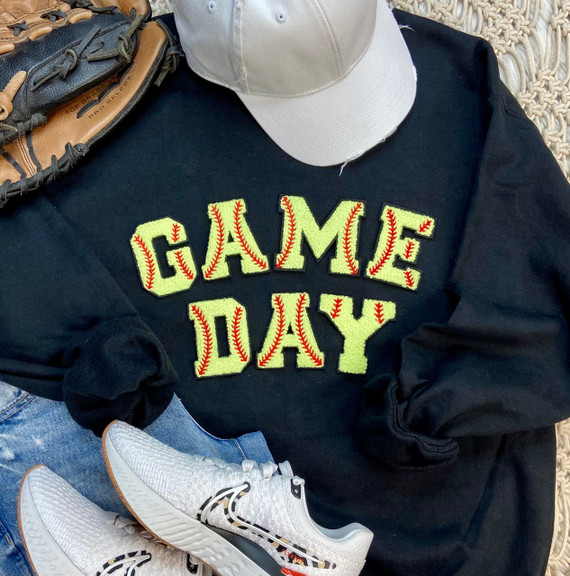 Softball Chenille Patch GAME DAY, close-up of the embroidered patch on a black sweatshirt with the words 'Game Day' decorated with red baseball stitching.