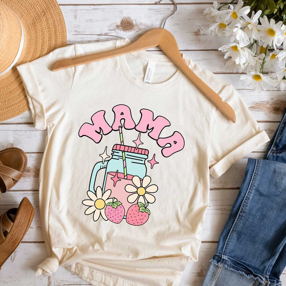 Mama Spring Drinks DTF Heat Transfer, colorful illustration of a mason jar with a straw, pink lettering spelling 'Mama', strawberries, and daisies on a white t-shirt.