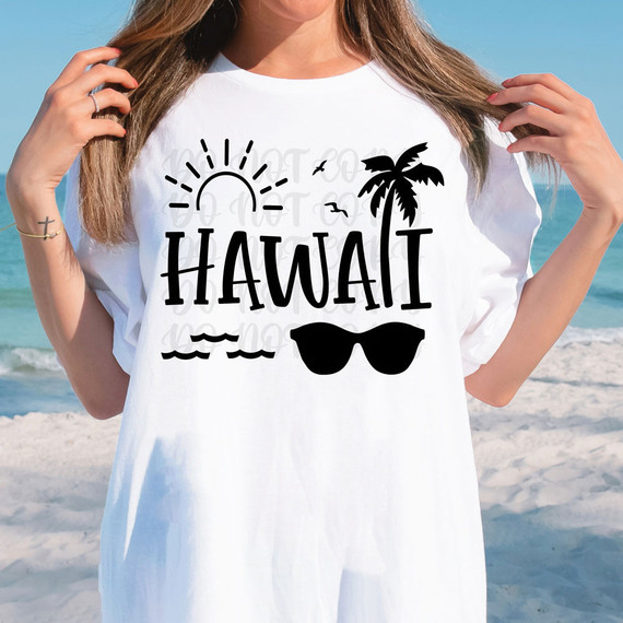 Hawaii DTF Heat Transfer, woman wearing a white T-shirt with black Hawaii-themed design including a sun, palm tree, sunglasses, and ocean waves, at the beach.