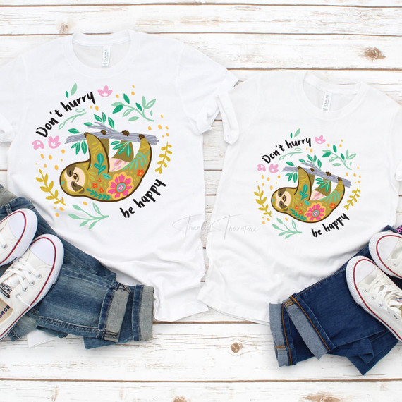 Don't Hurry Be Happy Sloth Sublimation Transfer, adorable sloth illustration on white T-shirts with floral decorations and cheerful message.