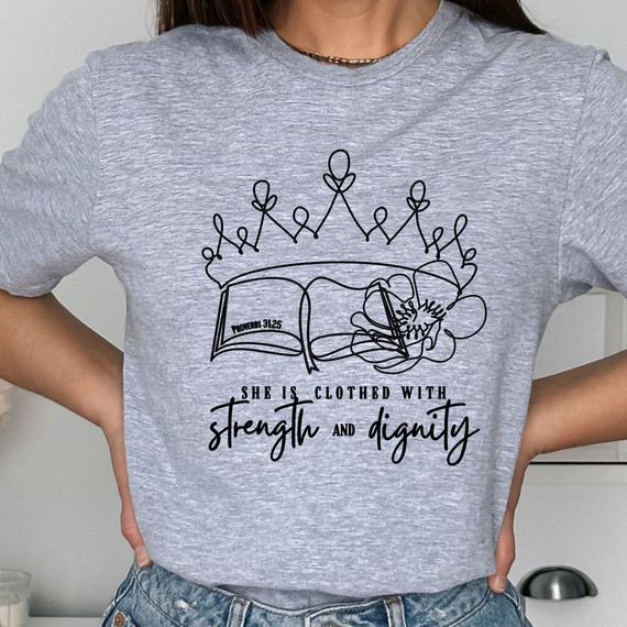 She Is Clothed With Strength And Dignity DTF Heat Transfer T-shirt, featuring a line art design of a crown, an open Bible with Proverbs 3:25, and floral elements, with the inspiring quote 'She is clothed with strength and dignity'.