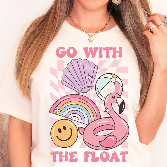 Go With The Float DTF Heat Transfer, colorful summer-themed design on a white T-shirt featuring a pink flamingo, seashell, rainbow, beach ball, and smiley face.