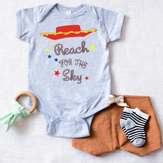 Reach for the Sky Jessie Fan Art Sublimation Transfer, a baby onesie with colorful star and cloud design featuring the phrase 'Reach for the Sky'.