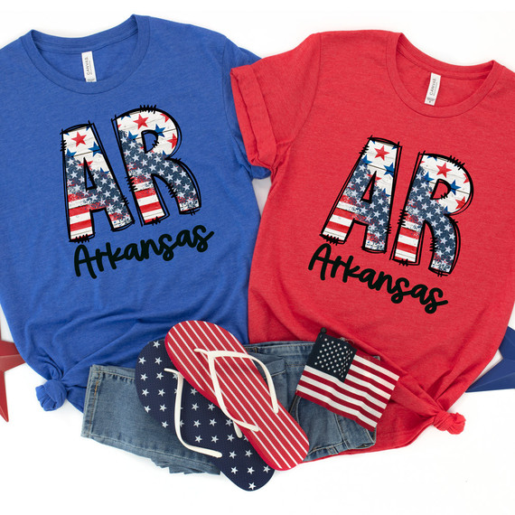 AR Stars & Stripes DTF Heat Transfer, on blue and red t-shirts with an American flag design and the text Arkansas, along with patriotic flip flops and a small American flag.