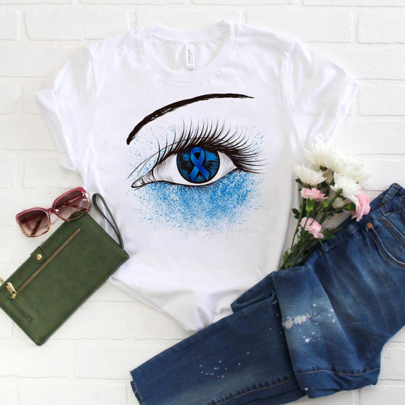 Blue Ribbon Awareness Glitter Eye Sublimation Transfer, graphic design of a blue eye with a blue awareness ribbon in the iris and glitter effects surrounding the eye on a white T-shirt.