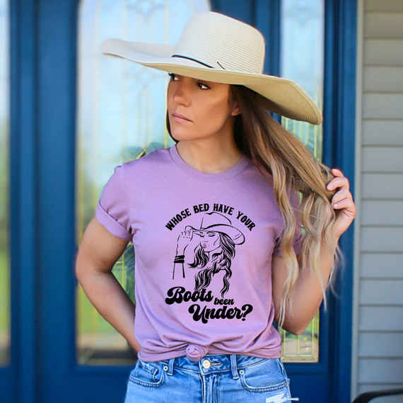 Whose Bed Have Your Boots Been Under? DTF Heat Transfer, a woman wearing a purple t-shirt with a stylish graphic of a woman with a hat and the text, outdoor setting with a blue door.