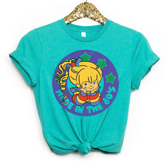 Made In The 80s DTF Heat Transfer, turquoise T-shirt featuring a colorful retro 1980s cartoon girl with a big blonde ponytail, stars, and vibrant design elements.