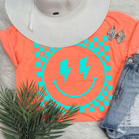 Checkered Happy Face MINT PUFF Screen Print Transfer, mint-colored smiley face with lightning bolt eyes on orange t-shirt, laid out with accessories and clothing items.