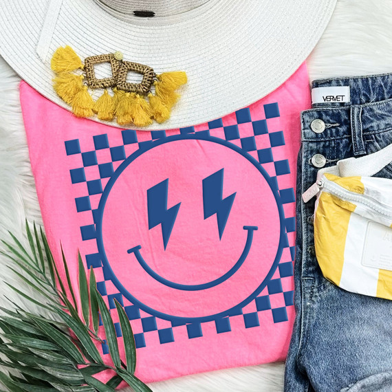 Checkered Happy Face DENIM PUFF Screen Print Heat Transfer, bright pink t-shirt with a blue happy face design featuring lightning bolt eyes and a smile, surrounded by a checkered pattern, fashion casual clothing accessory.