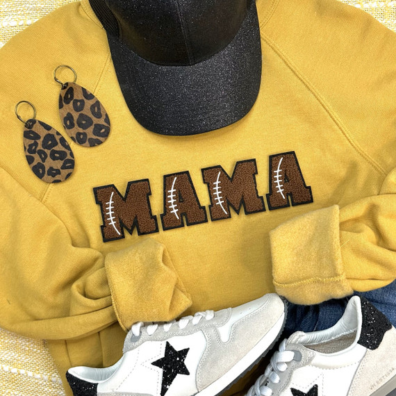 Football Chenille Embroidered Patch MAMA, close-up of a yellow sweatshirt with the embroidered patch, leopard print earrings, white sneakers with black star design, and a black glittery cap.
