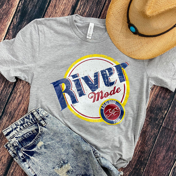 River Mode DTF Heat Transfer, close-up of a graphic design on a grey t-shirt with a casual summer outfit including a straw hat and distressed denim jeans on a wooden background.
