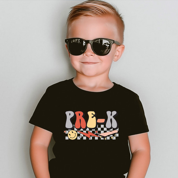 Pre-K Lightning Bolt DTF Heat Transfer, a colorful and playful design featuring the word 'PRE-K' with lightning bolt and smiley face elements on a black t-shirt worn by a young boy.