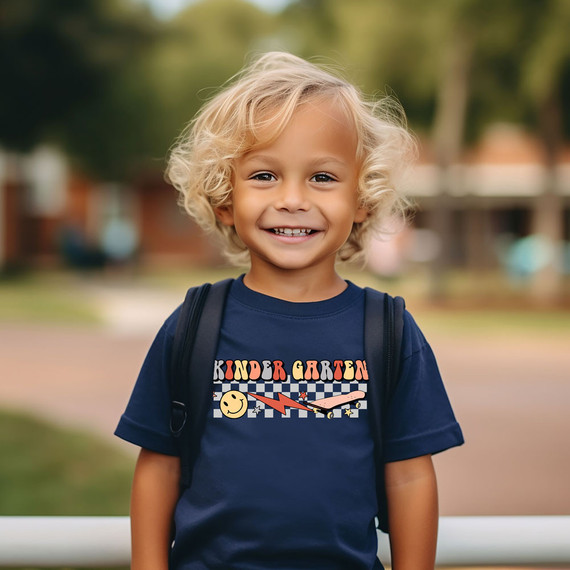 Kindergarten Lightning Bolt DTF Heat Transfer, a colorful and playful design on a navy blue children's T-shirt worn by a smiling kid.