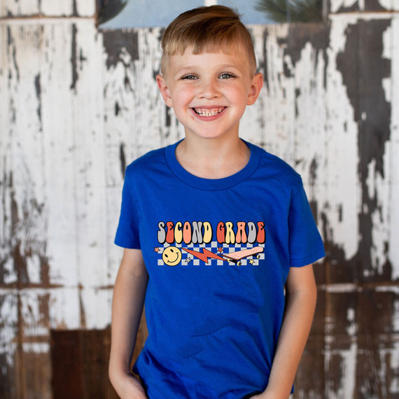 Second Grade Lightning Bolt DTF Heat Transfer, a colorful graphic design featuring the words 'Second Grade' with lightning bolt and star accents on a young boy's blue t-shirt.