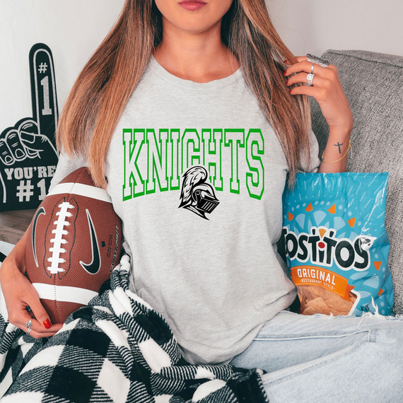 Knights *CUSTOM COLOR OPTIONS* DTF Heat Transfer, woman wearing a gray T-shirt with green and black Knights logo, sitting on a sofa with snacks and football.