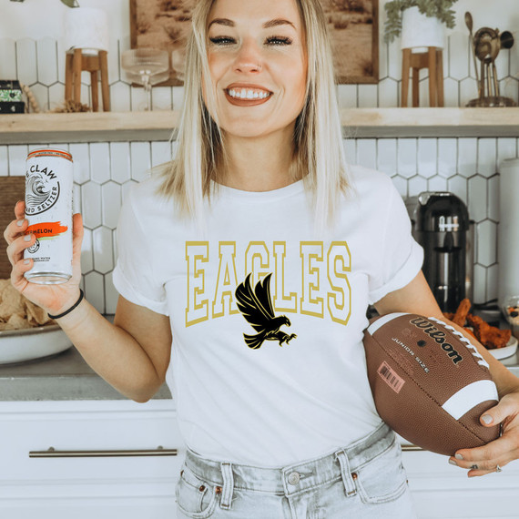 Eagles Custom Color Options DTF Heat Transfer, woman wearing a white t-shirt with Eagles logo and holding a football in a modern kitchen.