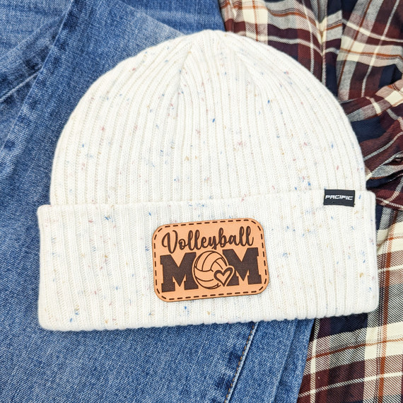 Volleyball Mom Leather Hat Patch, a rectangular leather patch with the words 'Volleyball MOM' and a volleyball graphic, sewn onto a cream-colored knitted hat.