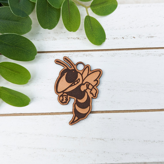 Yellowjacket Mascot Leather Keychain, a detailed cartoon-style yellowjacket insect keychain on a white wooden surface with green leaves.