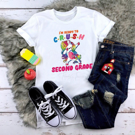 Back To School Dabbing Unicorns Second Grade Sublimation Transfer T-shirt, featuring a colorful unicorn design with the text "I'm Ready to Crush" and "Second Grade," laid out with denim shorts, sneakers, and school-themed accessories.