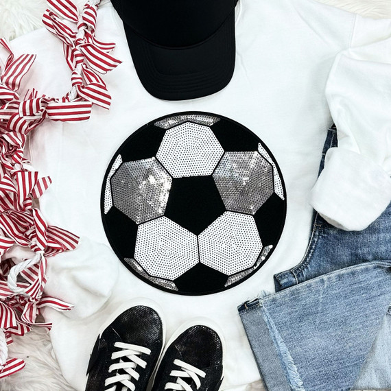 Sequins Soccer Patch Chenille Patch, decorative soccer ball patch with black, white, and silver sequins, on a flat lay of casual apparel and accessories including jeans, sneakers, a baseball cap, and a striped ribbon.