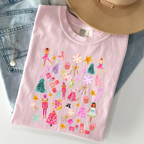 Pink Nutcracker Collage DTF Heat Transfer, colorful festive design with nutcrackers, candy canes, stars, Christmas trees, and holiday sweets on a pink T-shirt.