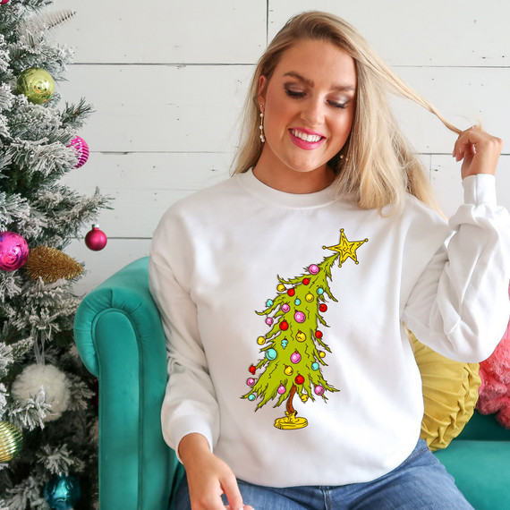 Little Tree DTF Heat Transfer, Christmas tree with colorful ornaments and star on top, on a woman's sweatshirt near a decorated Christmas tree.