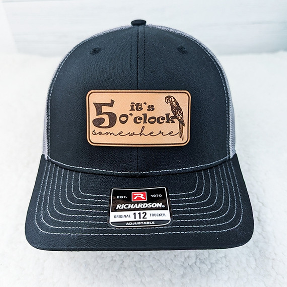 It's 5 o'clock Somewhere Parrot Leather Hat Patch, a black baseball cap featuring a leather patch with text and a parrot illustration.