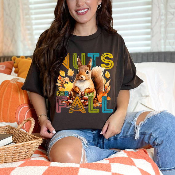 Nuts For Fall DTF Heat Transfer, a woman wearing a dark T-shirt with a colorful squirrel and fall-themed design with autumn leaves and nuts.