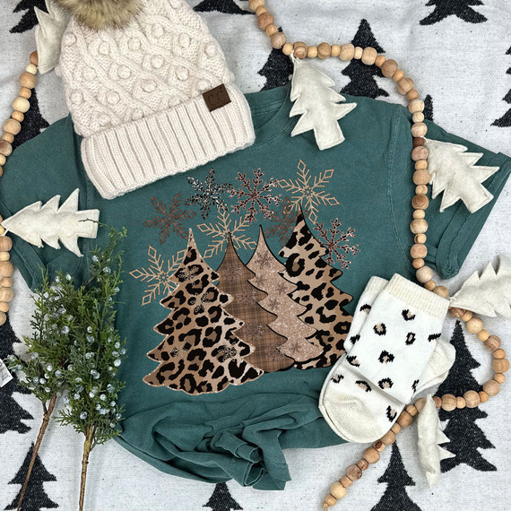 Leopard Christmas Trees DTF Heat Transfer, Christmas-themed teal sweatshirt with leopard print and plaid design, surrounded by holiday decorations and white mittens.