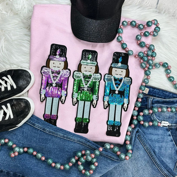 Nutcracker Sequins Embroidered Patch Bundle, colorful sequined nutcracker patches with detailed embroidered design on a pink shirt, paired with blue denim jeans, black sneakers, pink and teal beaded necklace, and black glittery hat.
