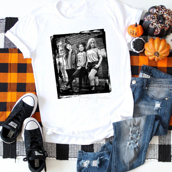 Hocus Pocus Fan Art Sublimation Transfer, Black and white printed image of three women on a white t-shirt, surrounded by Halloween-themed decorations and casual clothing accessories.