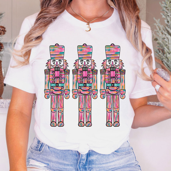 Watercolor Nutcracker Sublimation Transfer, vibrant colorful nutcracker design on a white T-shirt with a woman showcasing the product.