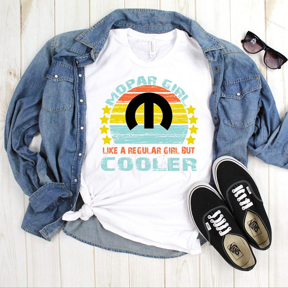 Mopar Girl Sublimation Transfer, T-shirt with colorful retro design and text, layered with a denim jacket, sunglasses, and sneakers on a wooden surface.