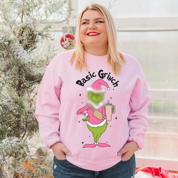 Basic Green Guy DTF Heat Transfer, a fun holiday-themed cartoon of the Grinch with a pink Santa hat and a mug, printed on a pink sweatshirt.