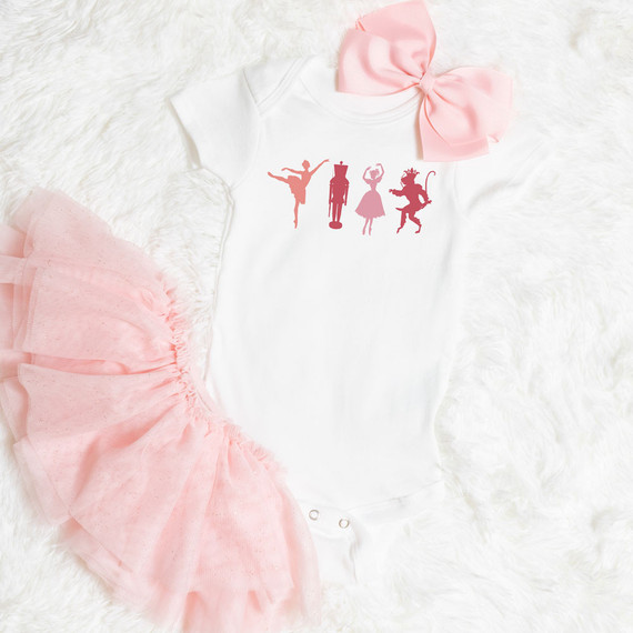 Nutcracker Dancers Sublimation Transfer, white baby onesie with ballet dancer silhouettes and pink bow, pink tutu, and fluffy white background.