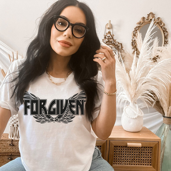 Forgiven Wings DTF Heat Transfer, woman wearing a white t-shirt with the Forgiven Wings logo, interior home decor background.
