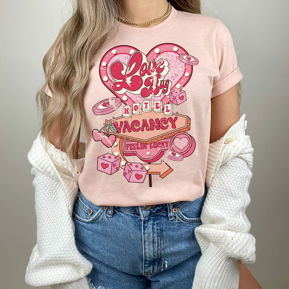 Love Bug Hotel DTF Heat Transfer, pink heart-themed design on a woman's pink t-shirt with love bug graphics and text.