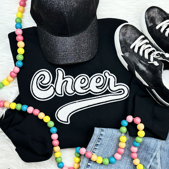 White Cheer Sequin Patch, a close-up of the embroidered patch on a black sweatshirt displayed with colorful bead necklaces, a glittery black cap, and casual sneakers.