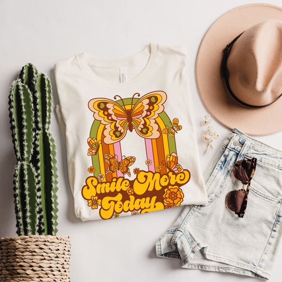 Smile More Today DTF Heat Transfer, colorful butterfly and floral design on a white T-shirt displayed with accessories.