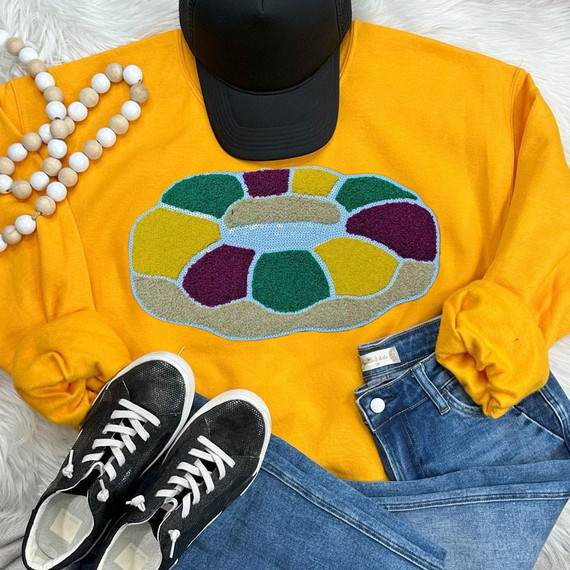 King Cake Sequin Chenille Patch, colorful stitched design of a king cake on a yellow sweatshirt.